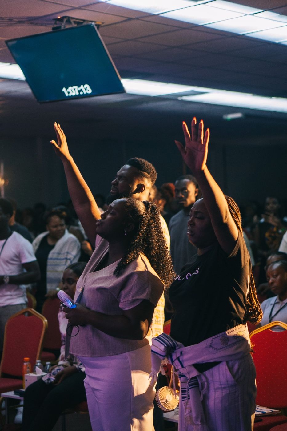 Young people worshipping with hands lifted at a Friday gathering